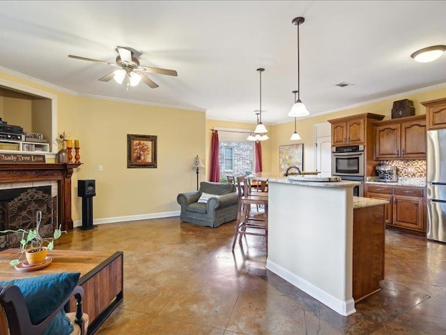 kitchen featuring crown molding, stainless steel appliances, an island with sink, and decorative light fixtures