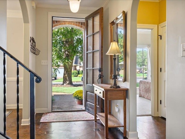 entrance foyer with ornamental molding and a healthy amount of sunlight