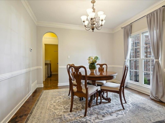 dining area with dark hardwood / wood-style floors, ornamental molding, and a chandelier