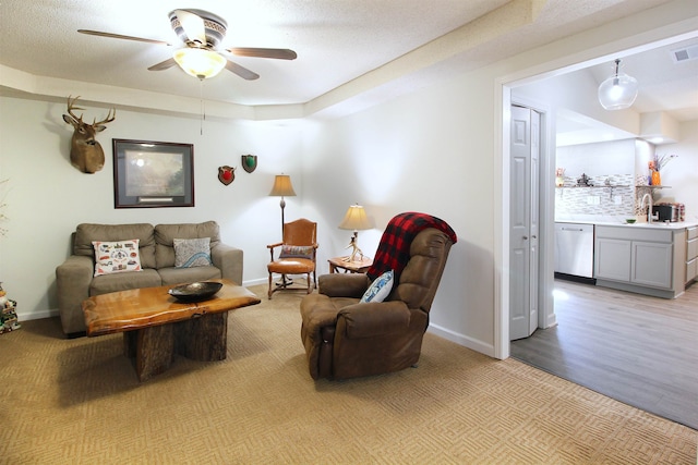 living room with a textured ceiling, ceiling fan, and light hardwood / wood-style flooring