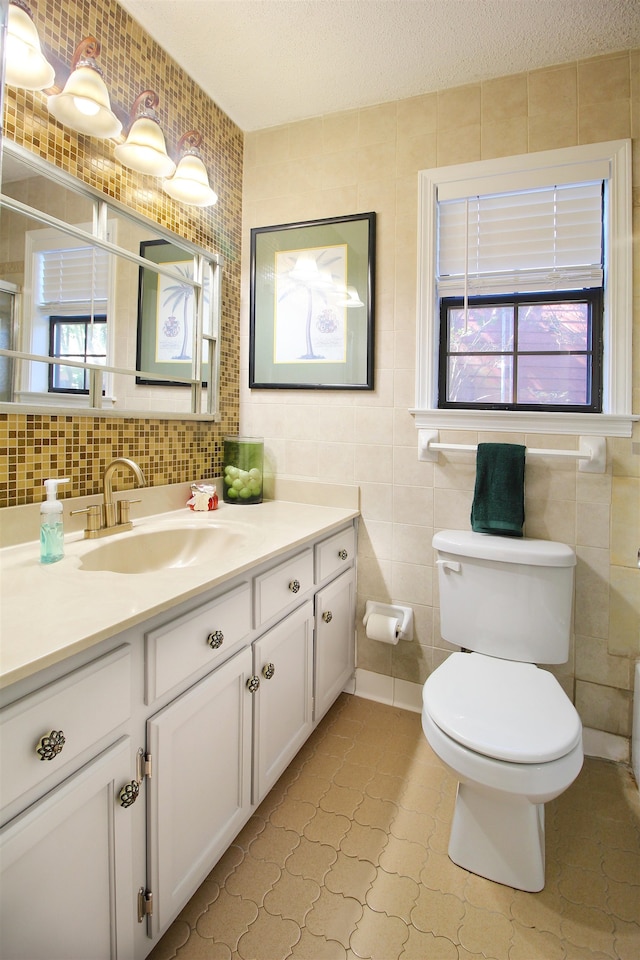 bathroom with tile walls, tile patterned flooring, a textured ceiling, vanity, and toilet