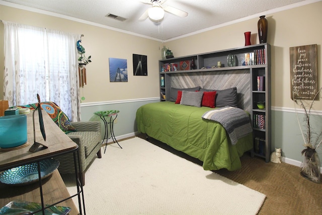 carpeted bedroom featuring ceiling fan, a textured ceiling, and ornamental molding