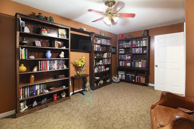 interior space featuring ceiling fan, a textured ceiling, and light carpet