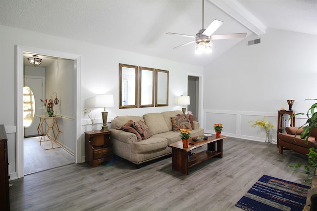 living room featuring lofted ceiling with beams, wood-type flooring, ceiling fan, and a textured ceiling