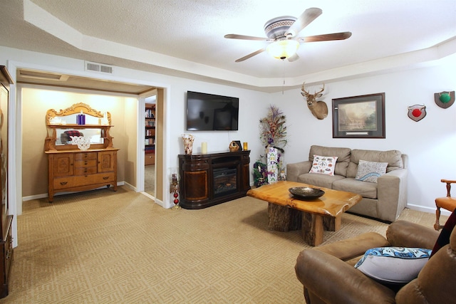 carpeted living room with ceiling fan, a textured ceiling, and a raised ceiling