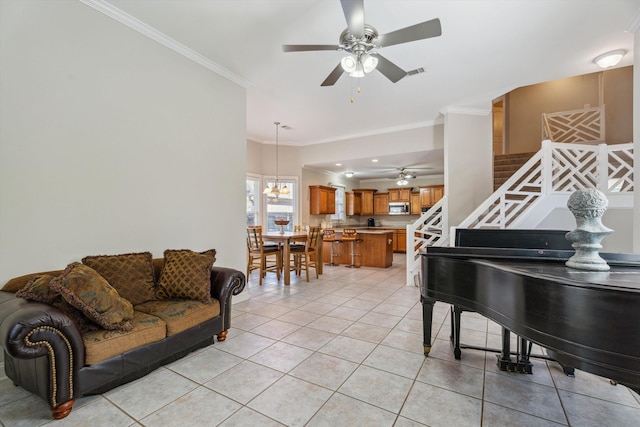 tiled living room with ceiling fan with notable chandelier and ornamental molding