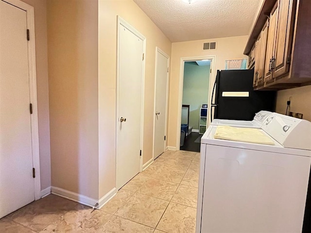 washroom featuring a textured ceiling, separate washer and dryer, and cabinets