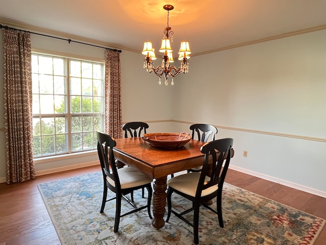 dining room featuring hardwood / wood-style flooring, ornamental molding, and an inviting chandelier