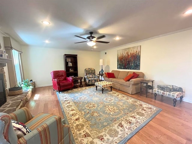 living room with ornamental molding, a fireplace, wood-type flooring, and ceiling fan