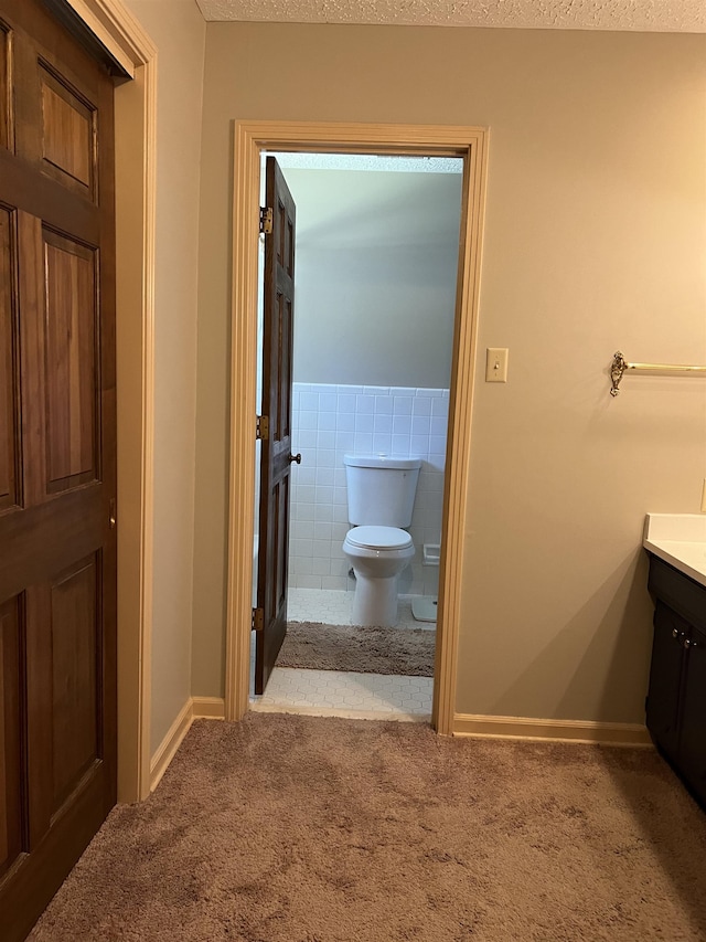 bathroom featuring vanity, tile walls, and toilet