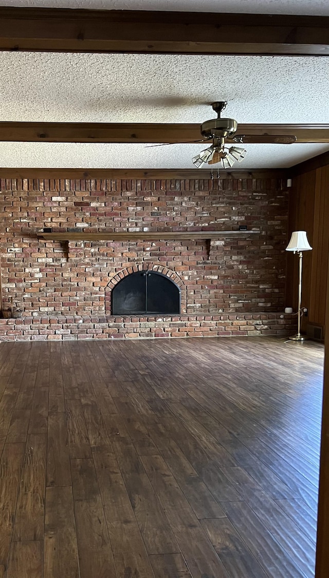 unfurnished living room with ceiling fan, wood walls, wood-type flooring, a textured ceiling, and a fireplace