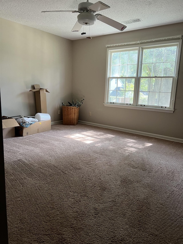 carpeted empty room featuring ceiling fan and a textured ceiling