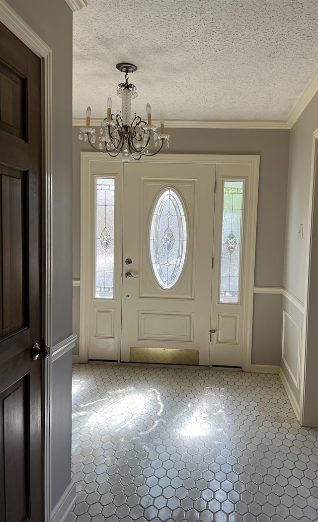 foyer featuring crown molding, a chandelier, and a textured ceiling