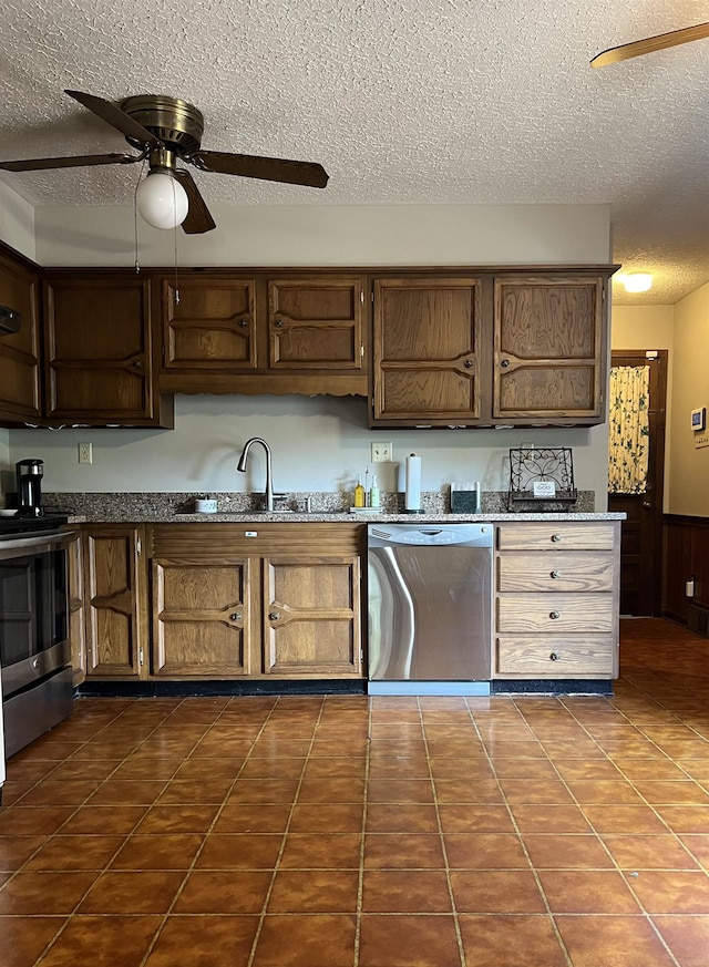 kitchen featuring sink, a textured ceiling, appliances with stainless steel finishes, dark tile patterned floors, and ceiling fan