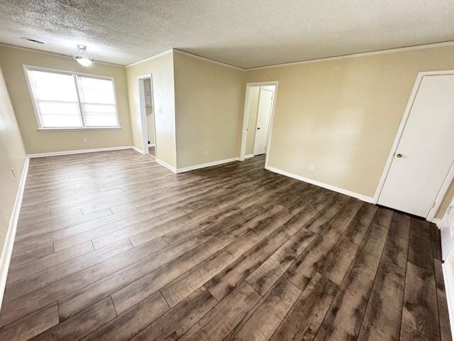 empty room featuring crown molding, dark hardwood / wood-style flooring, and a textured ceiling