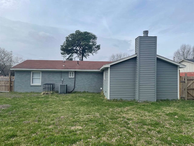 rear view of house with cooling unit and a lawn