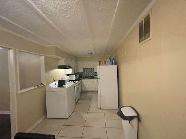 kitchen with light tile patterned floors, white appliances, a textured ceiling, backsplash, and washing machine and dryer