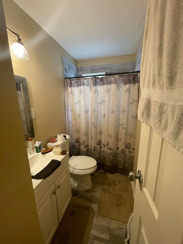 bathroom featuring a shower with shower curtain, a textured ceiling, vanity, and toilet