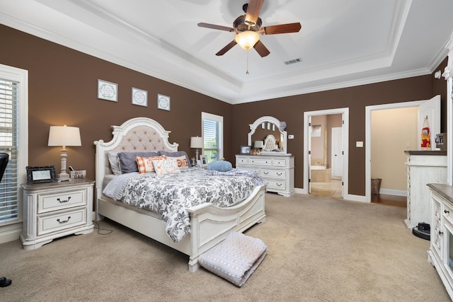 bedroom with connected bathroom, crown molding, a tray ceiling, ceiling fan, and light carpet