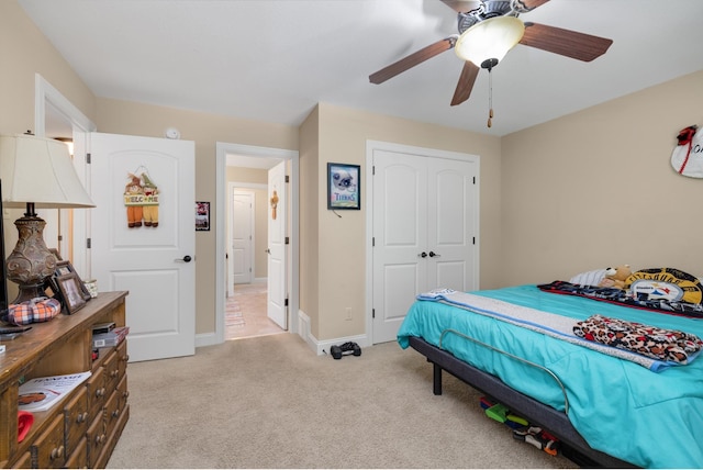 bedroom with ceiling fan, light colored carpet, and a closet