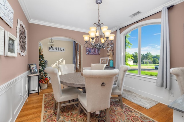 dining area featuring a chandelier, light hardwood / wood-style floors, and crown molding