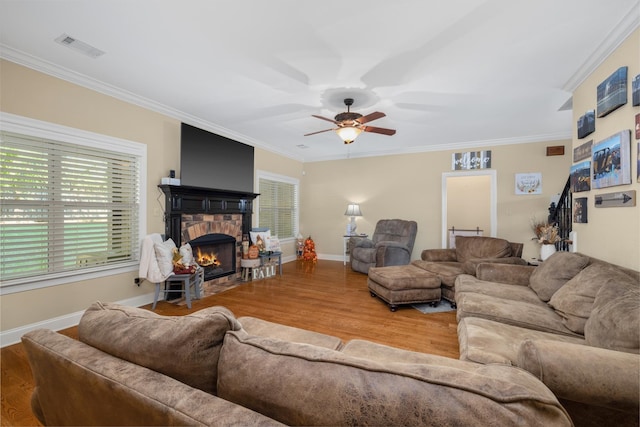 living room featuring crown molding, light hardwood / wood-style floors, a fireplace, and plenty of natural light