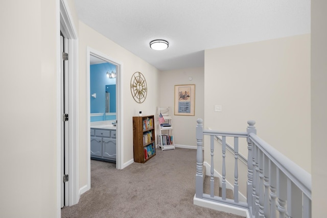 hallway featuring light carpet, sink, and a textured ceiling