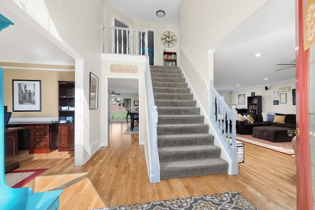 entrance foyer with hardwood / wood-style flooring, ceiling fan, and a high ceiling