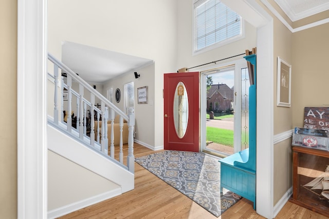 foyer entrance featuring hardwood / wood-style floors, a towering ceiling, and ornamental molding