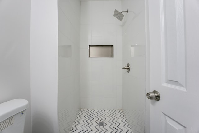 bathroom with tiled shower and toilet