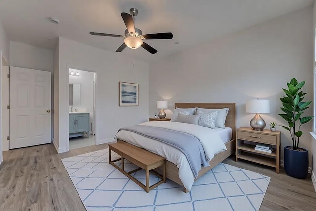 bedroom featuring connected bathroom, light hardwood / wood-style flooring, and ceiling fan