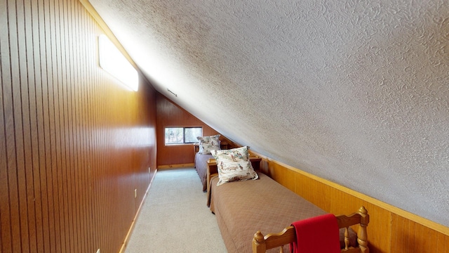 interior space with lofted ceiling, wooden walls, light carpet, and a textured ceiling