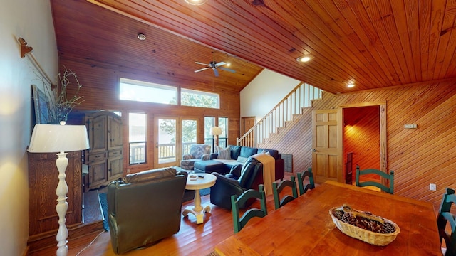 living room featuring wood ceiling, ceiling fan, wooden walls, light hardwood / wood-style floors, and lofted ceiling