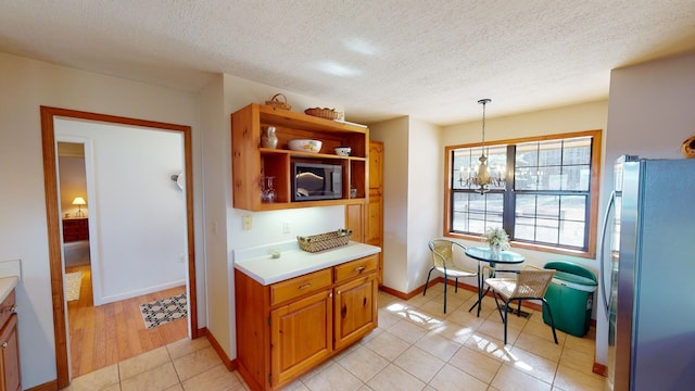 kitchen featuring stainless steel fridge, a textured ceiling, light tile patterned floors, decorative light fixtures, and an inviting chandelier