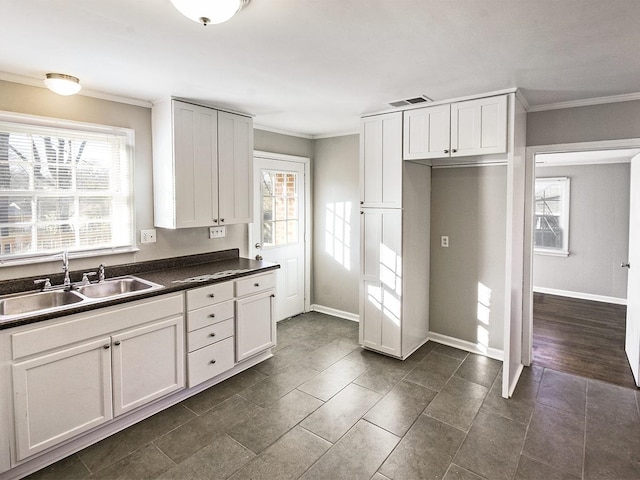 kitchen with crown molding, sink, dark tile patterned floors, and white cabinetry