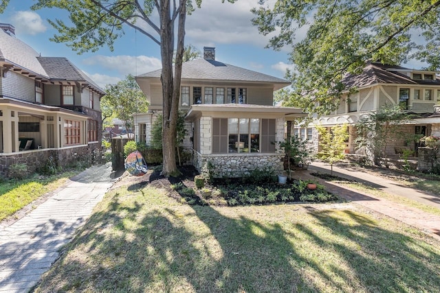 view of front of home with a sunroom and a front lawn