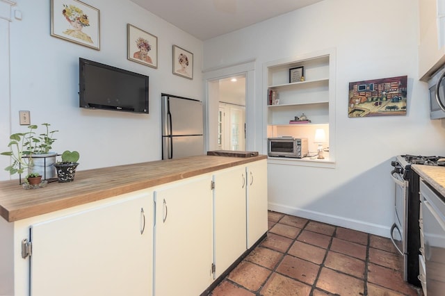 kitchen with appliances with stainless steel finishes, wooden counters, and white cabinets