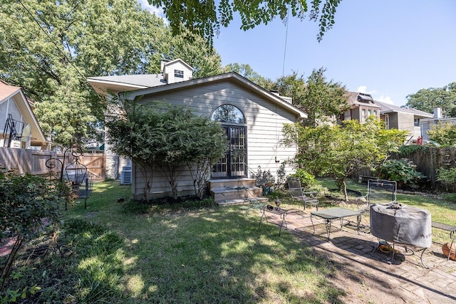 back of property featuring a yard, entry steps, and fence