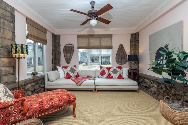 living area featuring ceiling fan, plenty of natural light, carpet, and ornamental molding