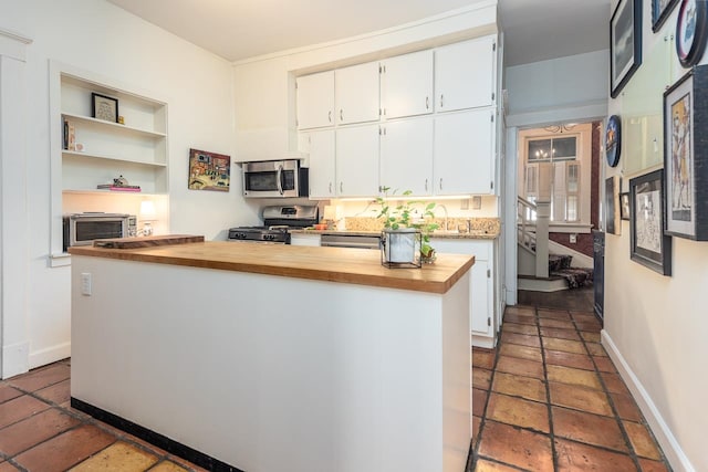 kitchen with white cabinets, appliances with stainless steel finishes, wood counters, and a kitchen island