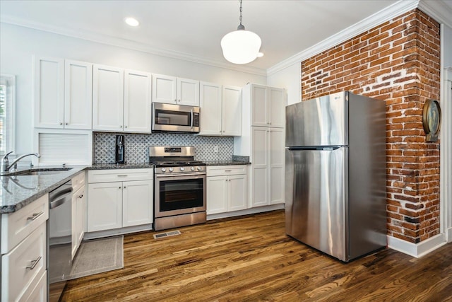 kitchen featuring a sink, appliances with stainless steel finishes, dark wood finished floors, crown molding, and backsplash