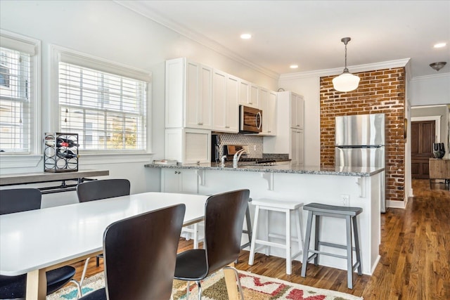 kitchen with dark wood-type flooring, white cabinets, stainless steel appliances, decorative light fixtures, and stone countertops