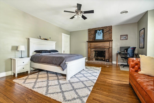 bedroom featuring ceiling fan, a fireplace, and dark wood-type flooring