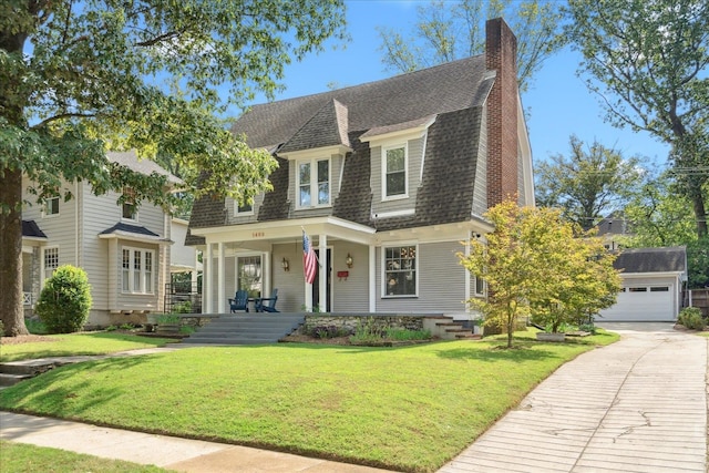 view of front of property featuring a garage, an outdoor structure, a porch, and a front lawn