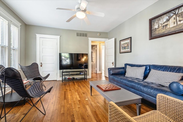 living room with visible vents, a ceiling fan, and wood finished floors