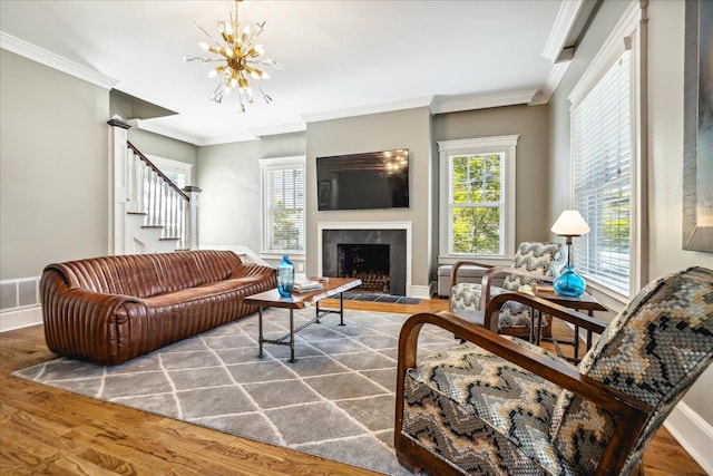 living room featuring ornamental molding, a chandelier, a fireplace, and hardwood / wood-style floors