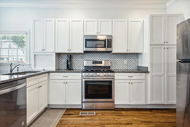 kitchen featuring appliances with stainless steel finishes, dark stone counters, white cabinetry, and sink