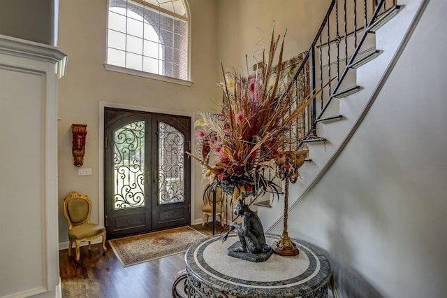 foyer featuring wood-type flooring, a high ceiling, and french doors