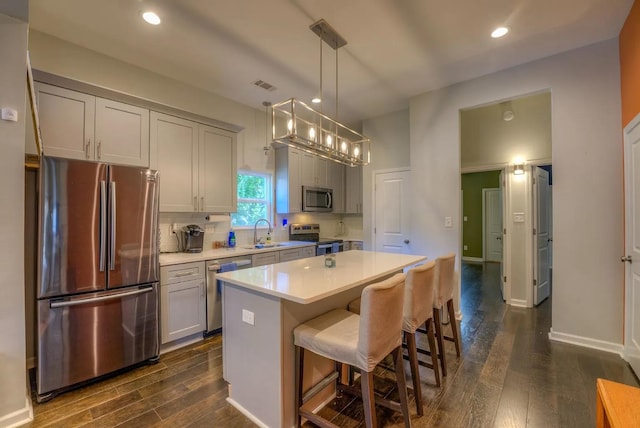 kitchen featuring decorative light fixtures, gray cabinets, stainless steel appliances, a center island, and dark hardwood / wood-style flooring