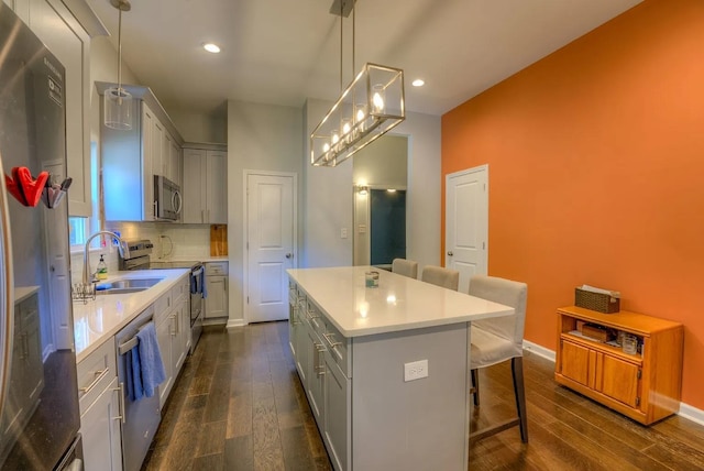 kitchen with stainless steel appliances, a center island, decorative light fixtures, and dark hardwood / wood-style flooring